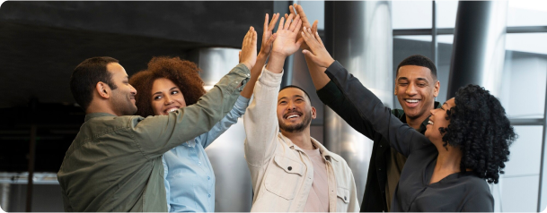 Grupo de cinco pessoas sorridentes dando um high five coletivo em ambiente corporativo moderno, simbolizando trabalho em equipe, celebração e colaboração.